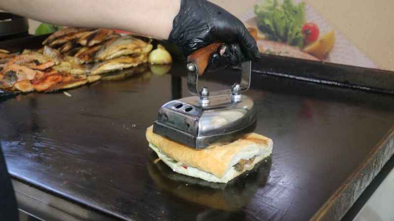 Ütü ile ekmek arası balıkları tost yapıp satıyor