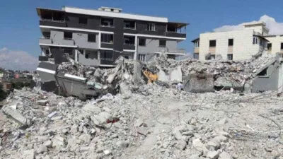 Ağır hasarlı binayı yıkan kepçe operatörü enkaz altında kaldı